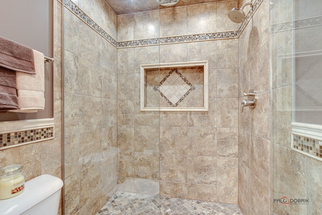 bathroom with tile walls, a tile shower, and toilet