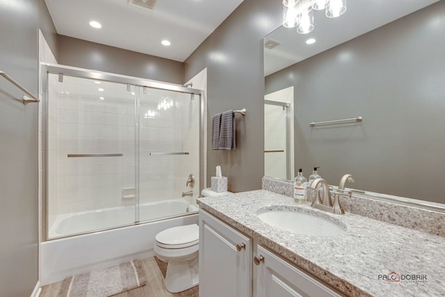 full bathroom featuring enclosed tub / shower combo, vanity, and toilet