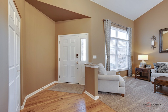 foyer entrance with lofted ceiling and light hardwood / wood-style flooring