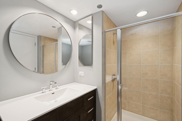 bathroom featuring a shower with door and vanity