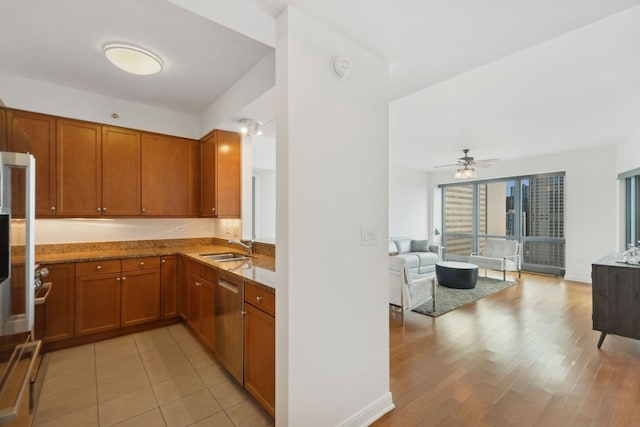 kitchen featuring sink, dishwasher, ceiling fan, light stone countertops, and light hardwood / wood-style floors