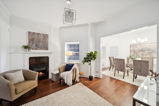 sitting room with crown molding, a tile fireplace, a chandelier, and dark hardwood / wood-style flooring