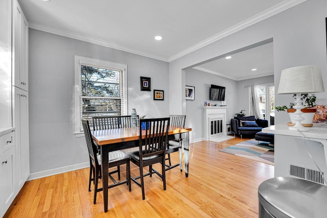 dining space with light hardwood / wood-style flooring, crown molding, and a healthy amount of sunlight