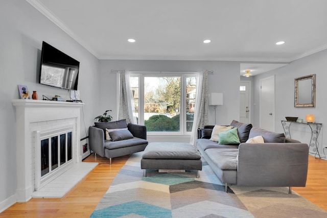 living room with a brick fireplace, ornamental molding, and light wood-type flooring