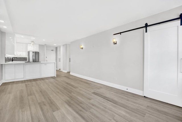 unfurnished living room featuring a barn door and light hardwood / wood-style flooring