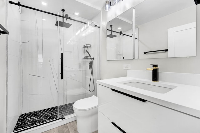 bathroom featuring hardwood / wood-style flooring, vanity, toilet, and a shower with shower door