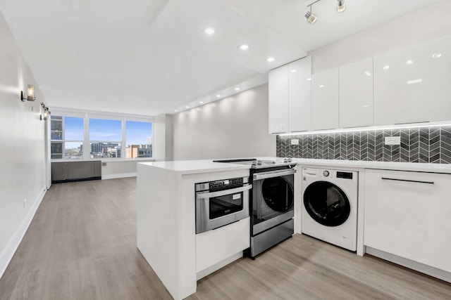 clothes washing area featuring separate washer and dryer and light wood-type flooring