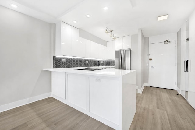 kitchen featuring kitchen peninsula, white cabinetry, stainless steel refrigerator, and light hardwood / wood-style floors