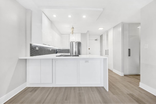 kitchen featuring kitchen peninsula, stainless steel fridge, white cabinets, and light hardwood / wood-style flooring