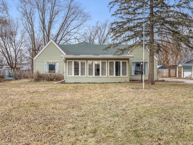 rear view of house featuring a lawn and a sunroom