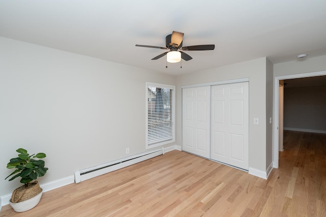 unfurnished bedroom with a baseboard radiator, light hardwood / wood-style floors, a closet, and ceiling fan