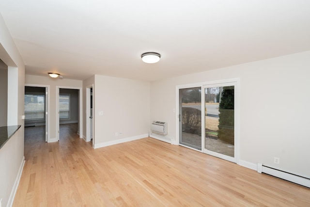 empty room featuring an AC wall unit, a healthy amount of sunlight, baseboard heating, and light hardwood / wood-style flooring