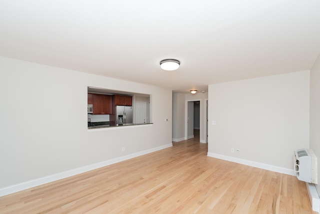 empty room with heating unit and light hardwood / wood-style floors