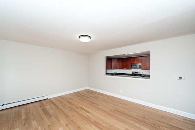 empty room featuring light hardwood / wood-style floors and a baseboard heating unit