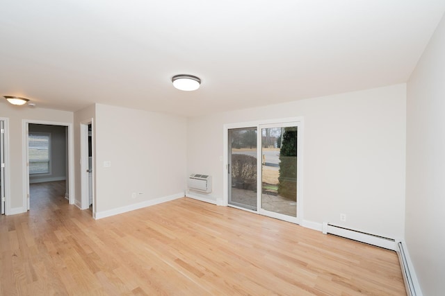 spare room featuring a baseboard radiator, plenty of natural light, and light hardwood / wood-style flooring