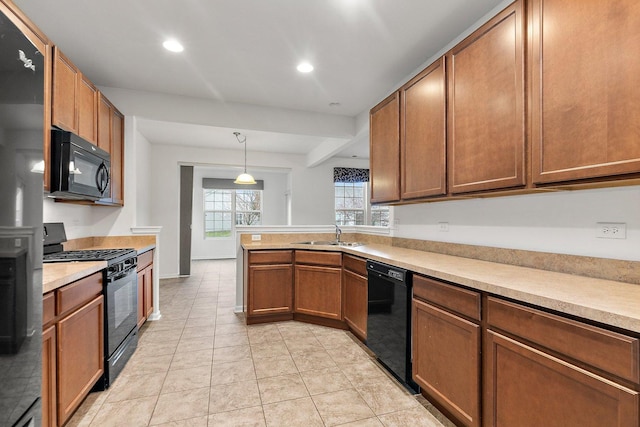 kitchen with kitchen peninsula, sink, black appliances, light tile patterned floors, and decorative light fixtures