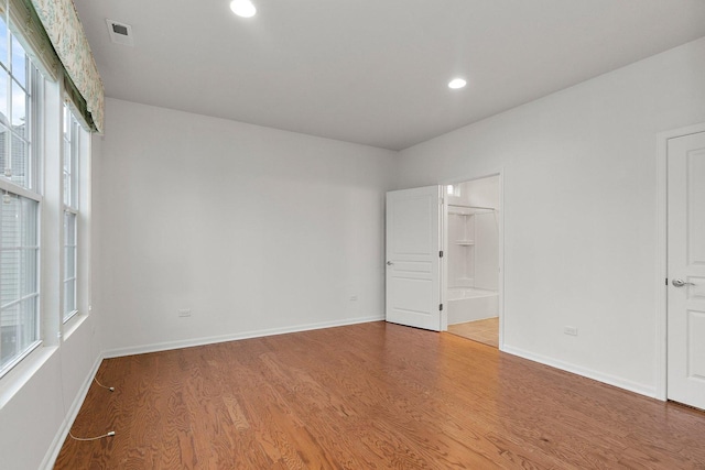 empty room with hardwood / wood-style floors and a healthy amount of sunlight