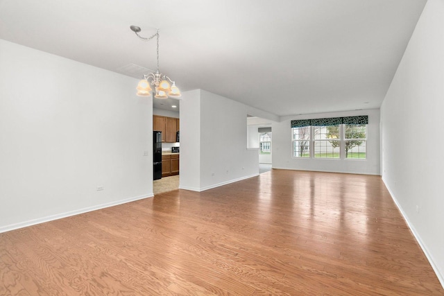 unfurnished living room with light hardwood / wood-style floors and an inviting chandelier