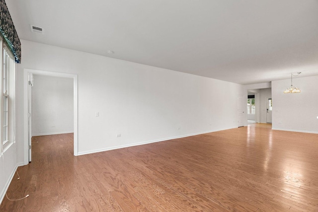 unfurnished room with a chandelier and hardwood / wood-style flooring