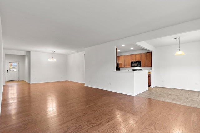 unfurnished living room with a notable chandelier and light wood-type flooring