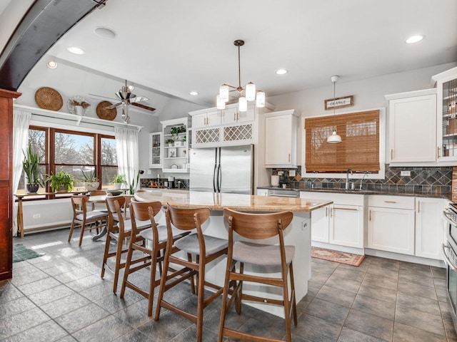 kitchen featuring white cabinetry, a center island, pendant lighting, and stainless steel refrigerator