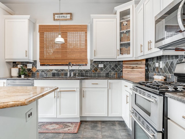 kitchen featuring sink, white cabinetry, decorative light fixtures, dark stone countertops, and stainless steel appliances