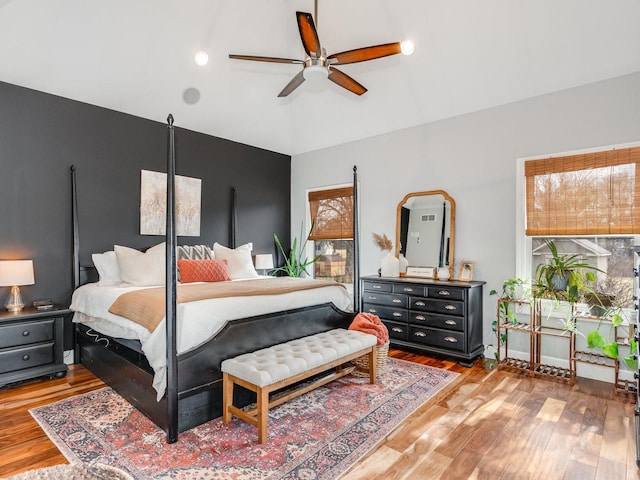 bedroom with multiple windows, a ceiling fan, vaulted ceiling, and wood finished floors