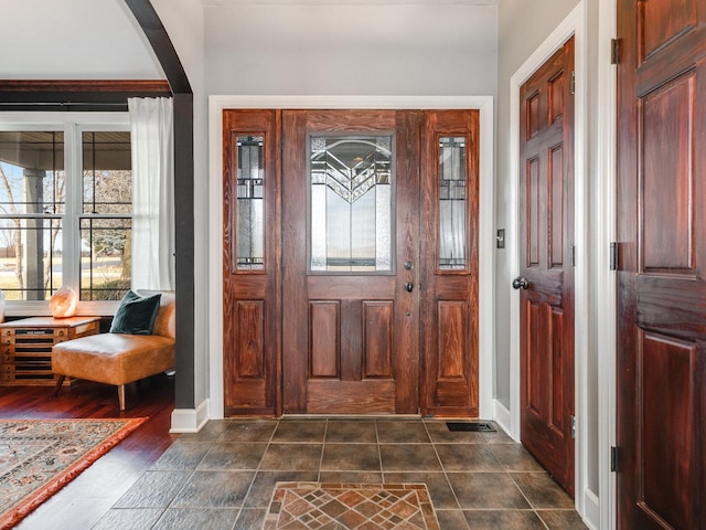 foyer with baseboards and arched walkways
