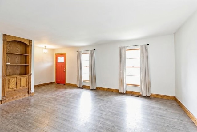 spare room featuring built in shelves and hardwood / wood-style flooring