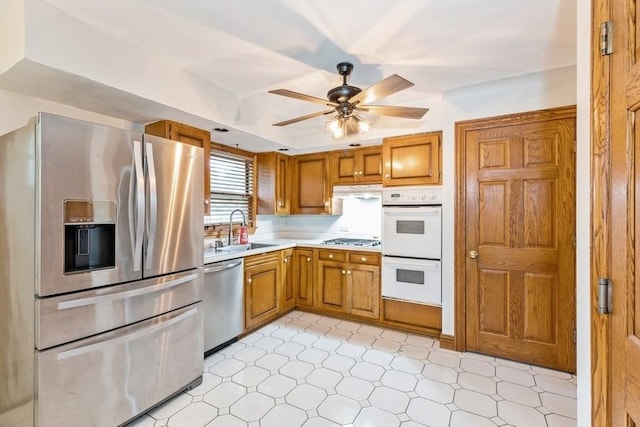 kitchen with ceiling fan, sink, stainless steel appliances, and a tray ceiling