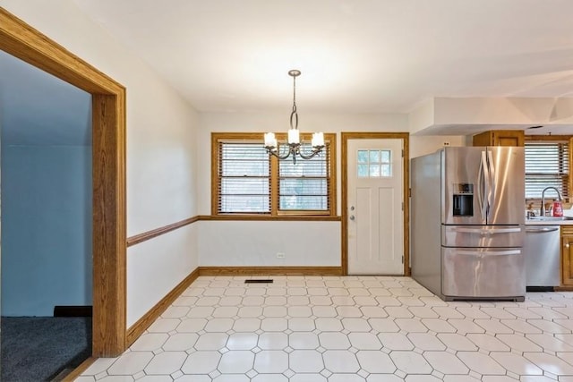 kitchen featuring a wealth of natural light, stainless steel appliances, sink, a notable chandelier, and hanging light fixtures