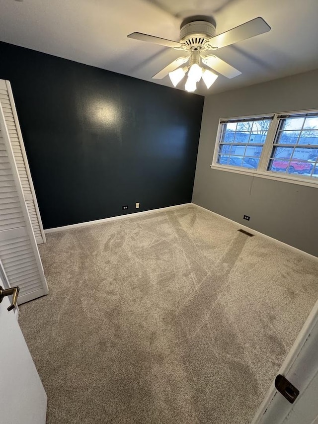 carpeted spare room featuring ceiling fan