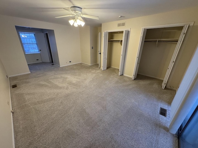 unfurnished bedroom featuring carpet, ceiling fan, and multiple closets