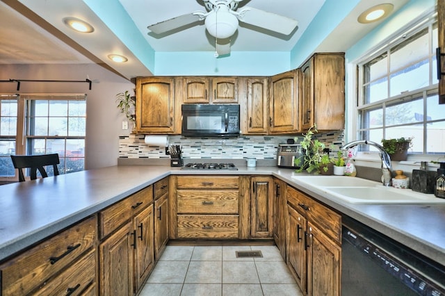 kitchen with kitchen peninsula, backsplash, sink, black appliances, and light tile patterned floors