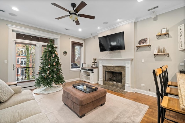 living room with crown molding, ceiling fan, and light hardwood / wood-style floors