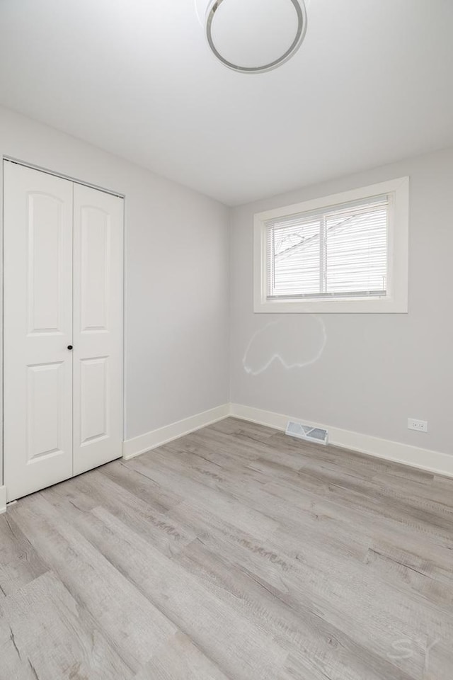 unfurnished bedroom with light wood-type flooring and a closet