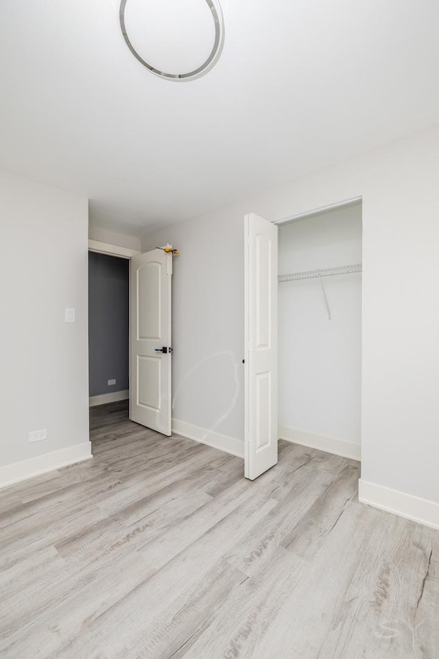 unfurnished bedroom with light hardwood / wood-style floors and a closet