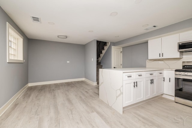 kitchen with kitchen peninsula, stainless steel appliances, white cabinets, and light hardwood / wood-style floors