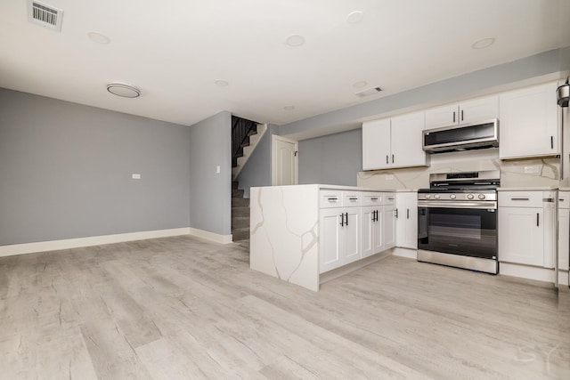 kitchen with light wood-type flooring, white cabinetry, and stainless steel range oven