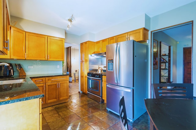 kitchen featuring sink, stainless steel appliances, dark stone counters, and decorative backsplash