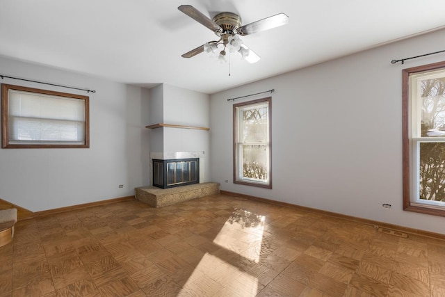 unfurnished living room featuring ceiling fan, a healthy amount of sunlight, and parquet floors