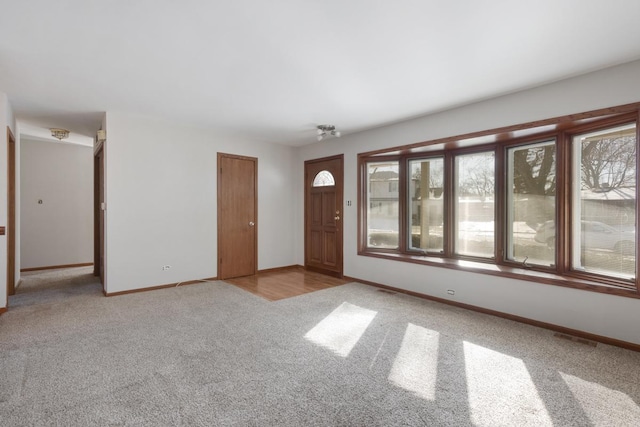 interior space featuring baseboards, visible vents, and light colored carpet