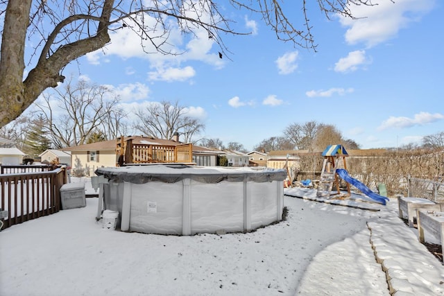 yard layered in snow featuring a playground and a pool side deck