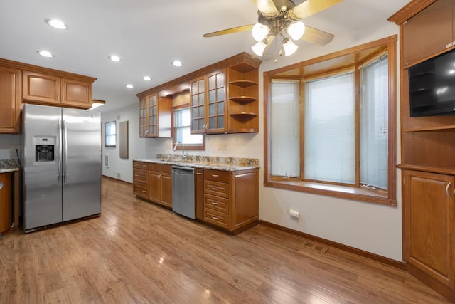 kitchen featuring sink, ceiling fan, light wood-type flooring, light stone countertops, and stainless steel appliances