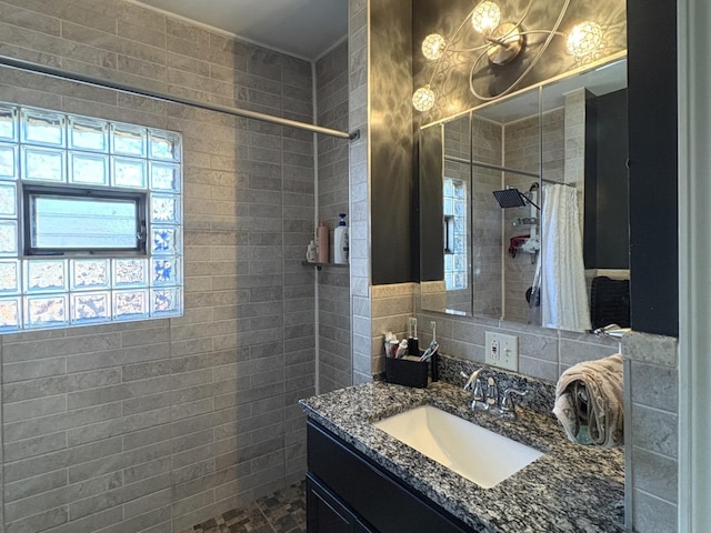 bathroom featuring vanity, curtained shower, and tile walls