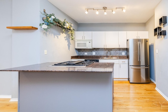 kitchen featuring white cabinetry, sink, light hardwood / wood-style flooring, backsplash, and appliances with stainless steel finishes