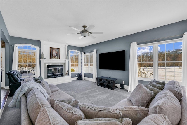 living room featuring a textured ceiling, carpet flooring, ceiling fan, and a large fireplace