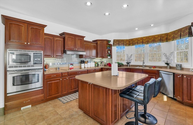 kitchen with a center island, stainless steel appliances, decorative backsplash, sink, and a breakfast bar