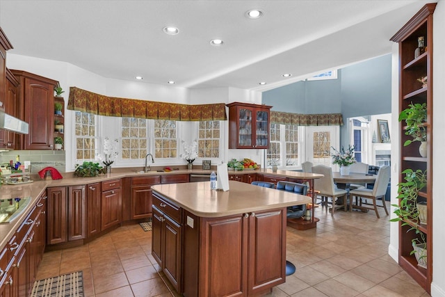 kitchen with light tile patterned flooring, stovetop, dishwasher, and a kitchen island