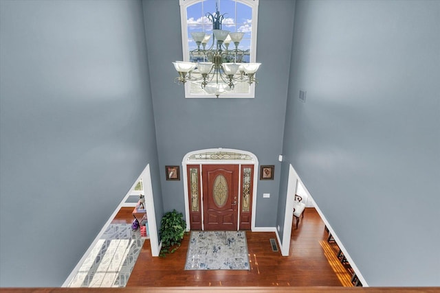 entrance foyer with dark hardwood / wood-style floors, a towering ceiling, and a notable chandelier